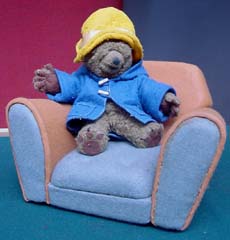 A cuddly Paddington bear seated in a miniature armchair.