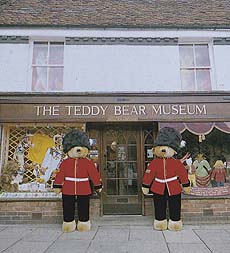 Outside view of an old-fashioned shopfront labelled 'The Teddy Bear Museum'. Two huge teddy bears dressed as member of the Household Cavalry are standing either side of the door.
