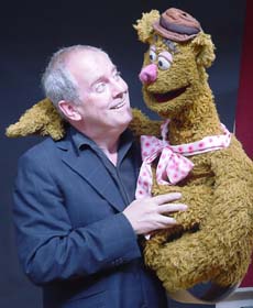 A man holding a large bear puppet.