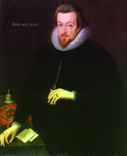 Shows an oil portrait of a man with a beard. His right hand rests on a table whilst his left holds a small bell, which is worn around his neck on a string. 