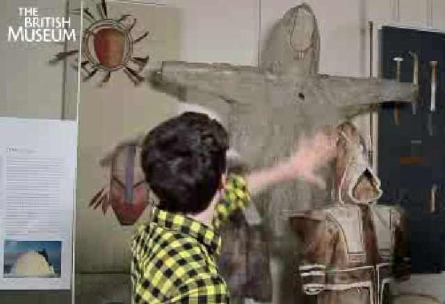 A screenshot showing a man gesturing to some native american clothes