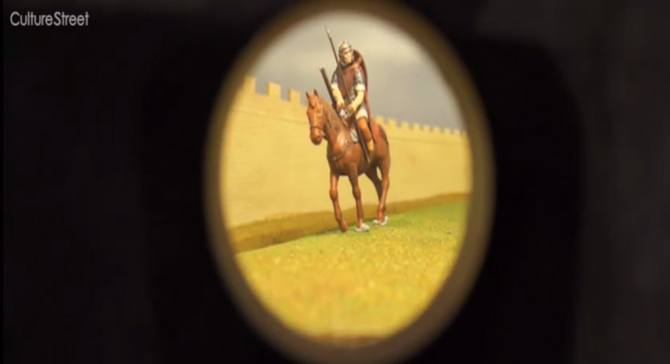 A screenshot showing a Roman solider on horseback through a peep hole. 