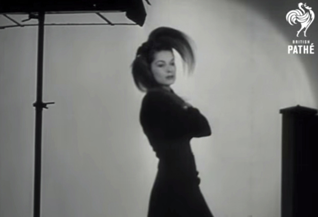 A black and white screenshot showing a glamorous fashion model