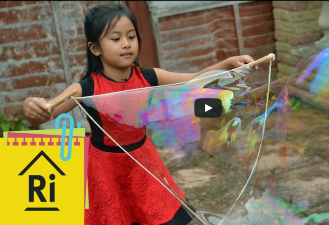 A screenshot showing a young girl making giant bubbles
