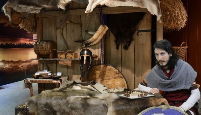 man in Viking style room and Viking clothing playing a board game