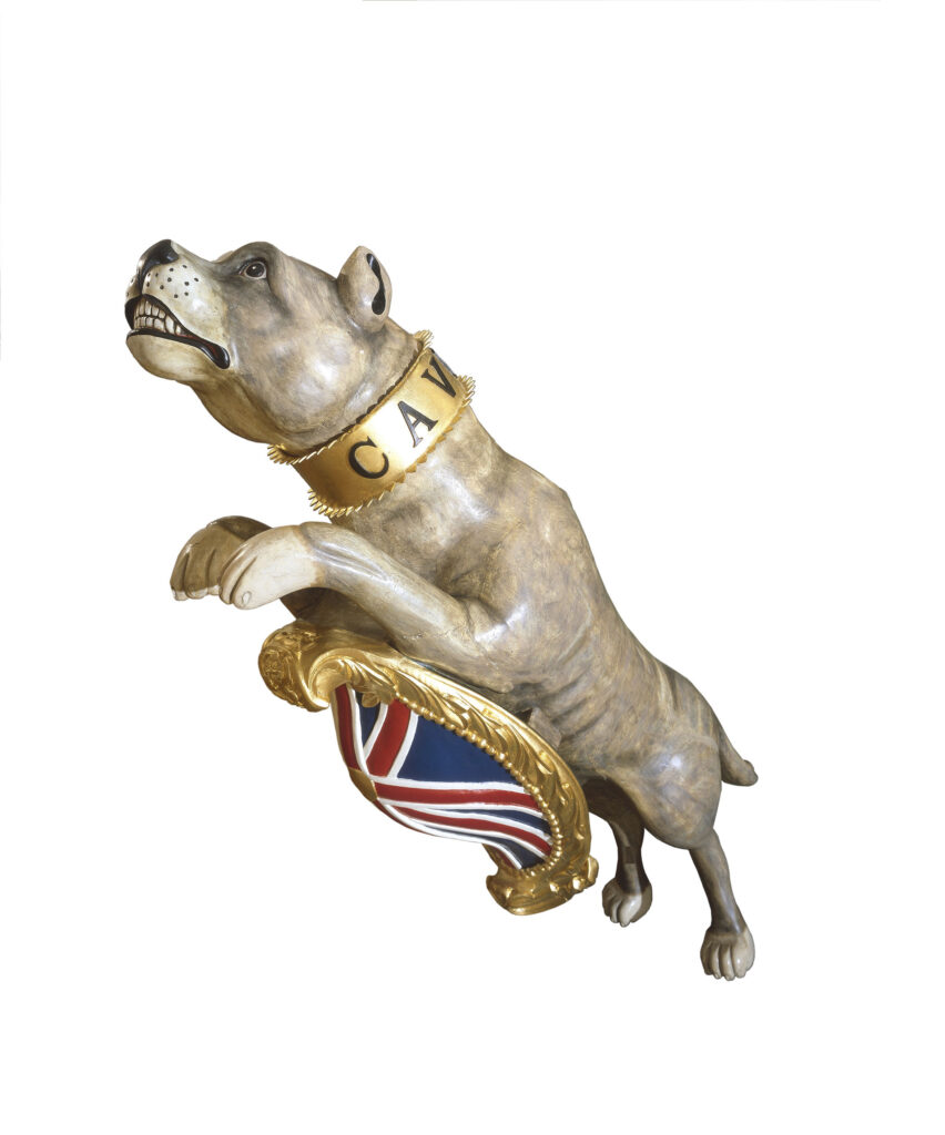 Figure head of a bulldog in leaping stance with union jack shield and collar engraved 'CAVE CANEM.'