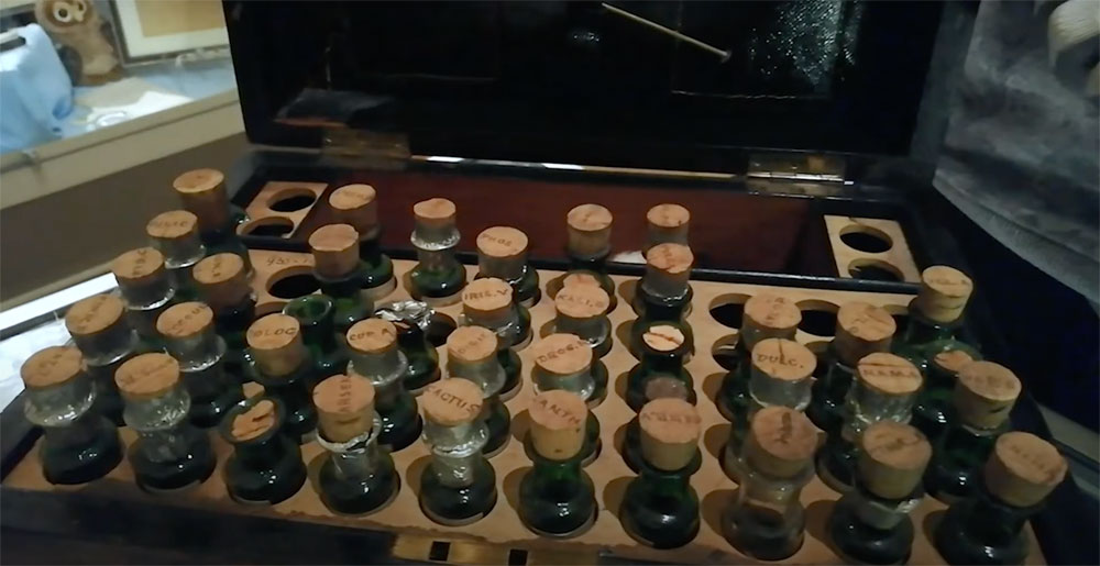 screenshot showing victorian wooden box containing small glass bottles sealed with cork lids