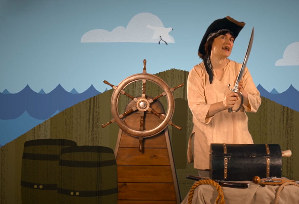 woman dressed as pirate holding sword with ship's wheel behind her and nautical backdrop